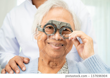 Optometrist checking Asian elderly woman ophthalmic vision eye test and using optical trial frame. Optometrist checking Asian elderly woman ophthalmic vision eye test and using optical trial frame. 137696904