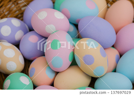 many colorful pastel decorated easter eggs in small wooden basket 137697029