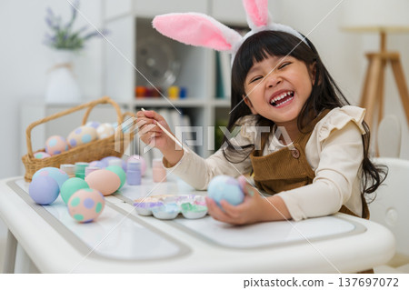 happy preschool child girl wearing bunny ears painting and decorating colorful egg at home on easter day happy preschool child girl wearing bunny ears painting and decorating colorful egg at home on easter day 137697072
