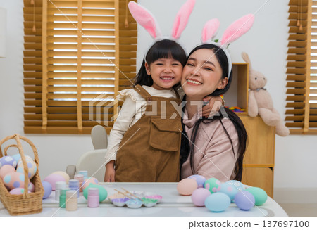 happy preschool child girl and mother hugging together while celebrating Easter day with colorful eggs on table at home happy preschool child girl and mother hugging together while celebrating Easter day with colorful eggs on table at home 137697100