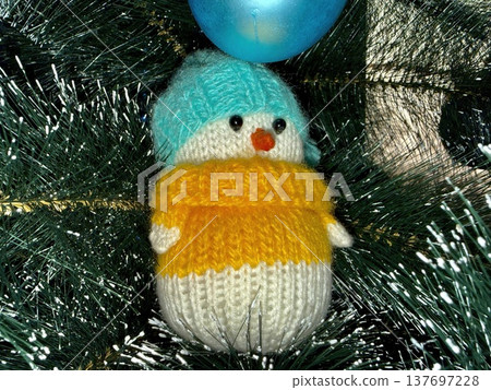 adorable knitted snowman ornament with blue hat and yellow sweater on christmas tree for holiday branding adorable knitted snowman ornament with blue hat and yellow sweater on christmas tree for holiday branding 137697228