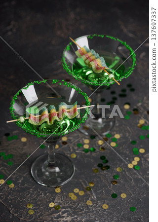 Green Cocktails with Rainbow Candy, shamrocks, Gifts and Confetti. Festive St. Patricks Day Celebration Still Life 137697337