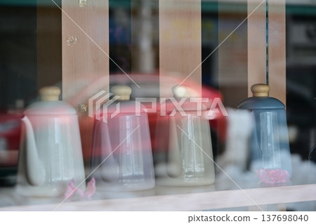 A stylish teapot visible through a shop window, reflected in the city skyline. A stylish teapot visible through a shop window, reflected in the city skyline. 137698040