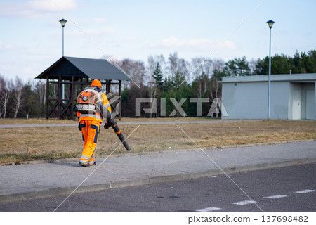 Road service worker in orange safety gear on empty highway Road service worker in orange safety gear on empty highway 137698482