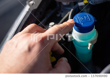 Hand opening blue cap of windshield washer reservoir Hand opening blue cap of windshield washer reservoir 137698490