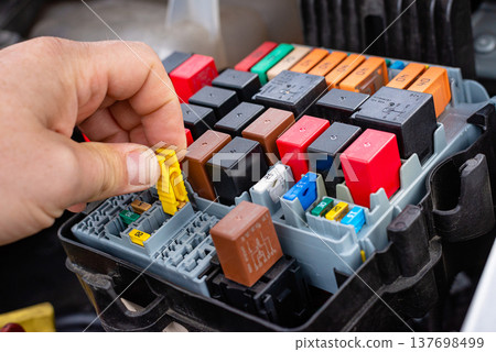 Hand pulling yellow fuse from car fuse box for replacement Hand pulling yellow fuse from car fuse box for replacement 137698499