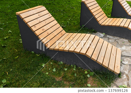 Modern wooden lounge benches set on green grass Modern wooden lounge benches set on green grass 137699126