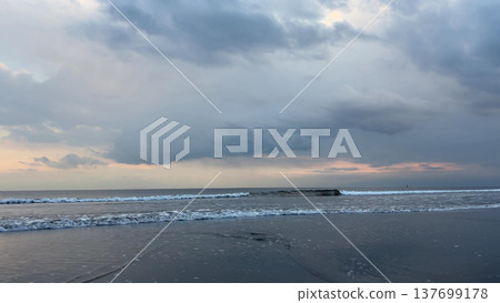 暮色中烏雲密布,白色的波浪拍打著海岸線。 暮色中烏雲密布,白色的波浪拍打著海岸線。 137699178