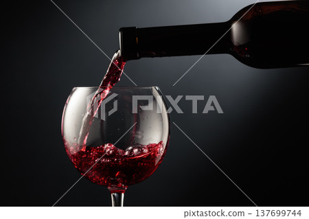 Pouring red wine into a wine glass. Pouring red wine into a wine glass. 137699744