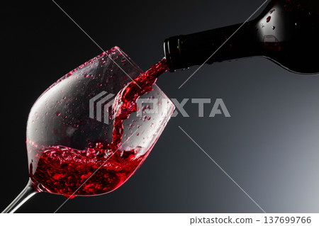 Red wine is poured from a bottle into a glass. Red wine is poured from a bottle into a glass. 137699766
