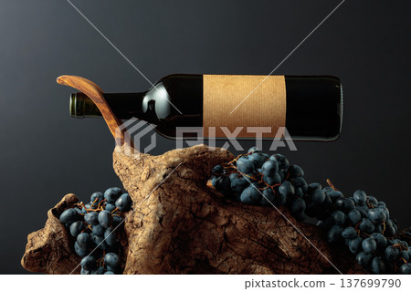 Unopened bottle of red wine, blue grapes, and old weathered snag. 137699790