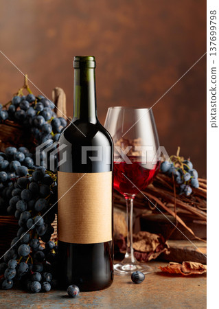 Bottle of red wine with blue grapes on a brown background. Bottle of red wine with blue grapes on a brown background. 137699798