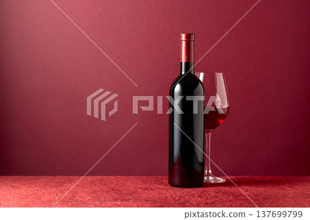 Bottle and glass of red wine on a red background. 137699799