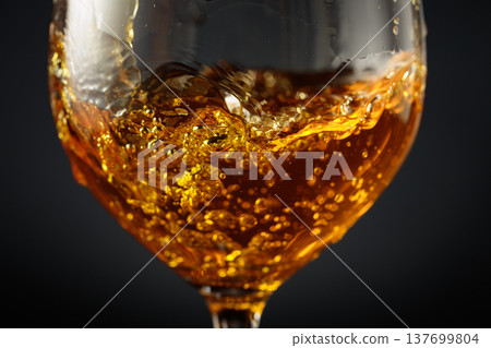 White wine of rich amber color being poured into a glass. White wine of rich amber color being poured into a glass. 137699804
