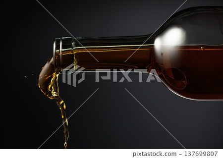 White wine of a rich amber color pours out of the bottle. White wine of a rich amber color pours out of the bottle. 137699807