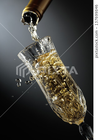 White sparkling wine is poured from a bottle into a glass. 137699846