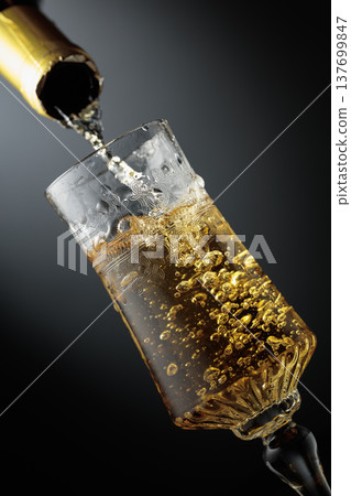 White sparkling wine is poured from a bottle into a glass. White sparkling wine is poured from a bottle into a glass. 137699847