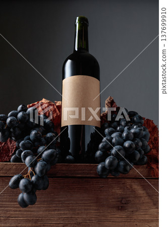 Red wine bottle with blue grapes on an old wooden table. Red wine bottle with blue grapes on an old wooden table. 137699910