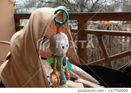 black and beige baby stroller with baby toy parked on balcony black and beige baby stroller with baby toy parked on balcony 137700609