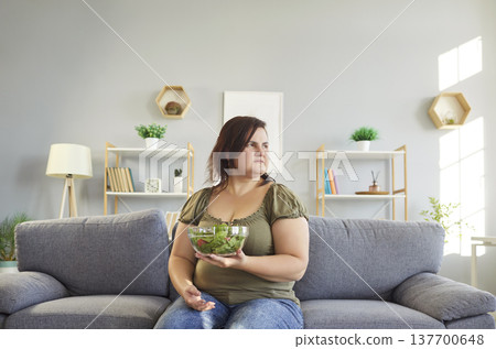 Obese woman sad with healthy salad, unhappy slimming vegetarian diet, eating green vegetables Obese woman sad with healthy salad, unhappy slimming vegetarian diet, eating green vegetables 137700648