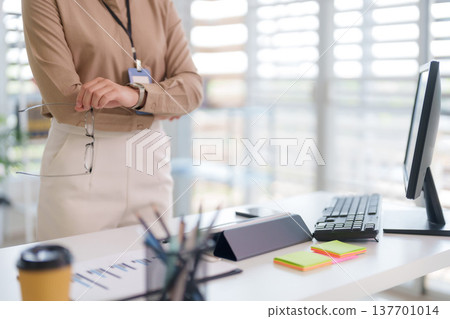 Asian adult woman standing holding eyeglasses modern office workplace professional environment business work desk office supplies corporate professionalism career Asian adult woman standing holding eyeglasses modern office workplace professional environment business work desk office supplies corporate professionalism career 137701014