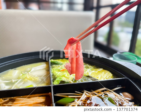 Shabu-shabu is a Japanese dish. Thinly sliced beef tongue is placed in a hot broth. Shabu-shabu is a Japanese dish. Thinly sliced beef tongue is placed in a hot broth. 137701374