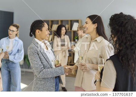Business women networking handshake at office event, colleagues greeting warmly Business women networking handshake at office event, colleagues greeting warmly 137701637