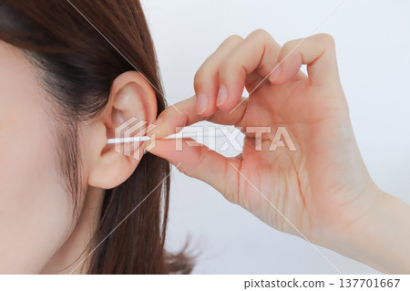 A woman cleaning her ears with a cotton swab 137701667