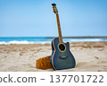 A guitar propped up against the ocean backdrop. 137701722