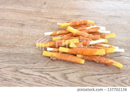 dog snack crunchy stick made from cow leather and bone wrapped chicken meat on table dog snack crunchy stick made from cow leather and bone wrapped chicken meat on table 137702136