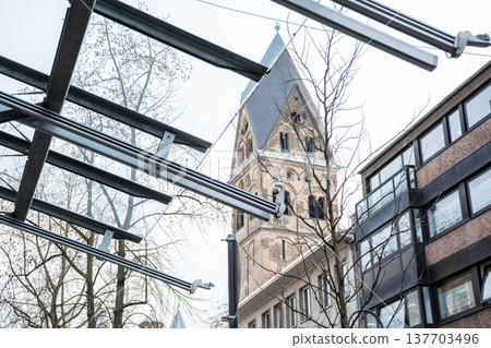 Basilica of St. Apostles in Cologne, Germany. The structure features two prominent towers and intricate architectural details against a cloudy sky. Basilica of St. Apostles in Cologne, Germany. The structure features two prominent towers and intricate architectural details against a cloudy sky. 137703496