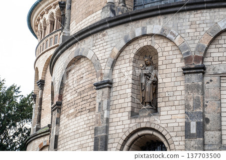 Basilica of St. Apostles in Cologne, Germany. The structure features two prominent towers and intricate architectural details against a cloudy sky. 137703500