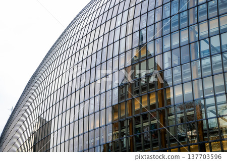 Antoniterkirche stands beside a modern urban building in Cologne, Germany. The church features a tall spire and traditional architecture, contrasting with the glass structure. Antoniterkirche stands beside a modern urban building in Cologne, Germany. The church features a tall spire and traditional architecture, contrasting with the glass structure. 137703596