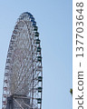 A giant Ferris wheel, a colossal ring soaring against the blue sky. 137703648