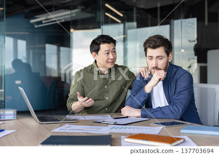 Mature asian business man offering support and empathy to a distressed male colleague in a modern office, showing teamwork and mental wellness at the workplace Mature asian business man offering support and empathy to a distressed male colleague in a modern office, showing teamwork and mental wellness at the workplace 137703694