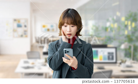 一位女士/女商人對她的智慧型手機螢幕感到驚訝 一位女士/女商人對她的智慧型手機螢幕感到驚訝 137705618