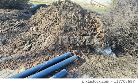 Excavation site with plastic utility pipes and soil pile for underground pipeline installation Excavation site with plastic utility pipes and soil pile for underground pipeline installation 137705697