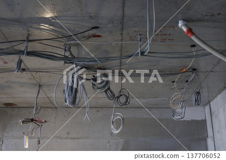 建築工地的混凝土天花板上架設電線和電纜。 建築工地的混凝土天花板上架設電線和電纜。 137706052