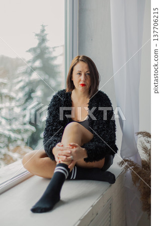 Beautiful woman posing on a large window in a 137706215