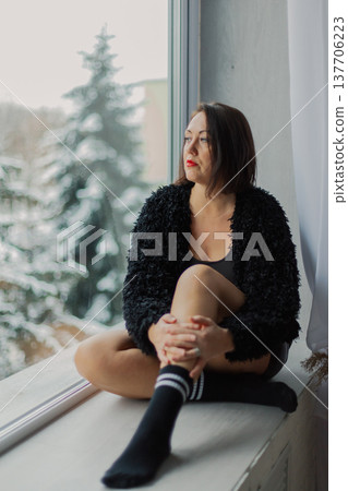 Beautiful woman posing on a large window in a 137706223