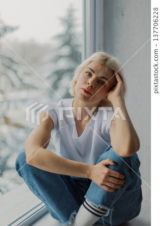 Beautiful woman posing on a large window in a Beautiful woman posing on a large window in a 137706228
