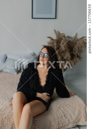 Beautiful woman posing for photographer on bed in 137706639