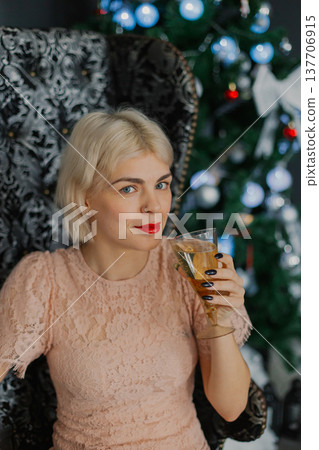 A woman sits on a chair near a Christmas tree with A woman sits on a chair near a Christmas tree with 137706915