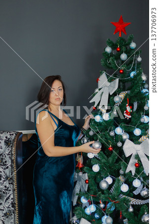 A woman stands near a Christmas tree and touches A woman stands near a Christmas tree and touches 137706973