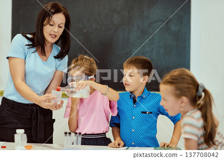 Teacher guiding elementary students through a hands-on science experiment as children learn in classroom Teacher guiding elementary students through a hands-on science experiment as children learn in classroom 137708042