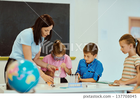 Teacher guiding children through a hands-on science experiment in a bright classroom 137708045