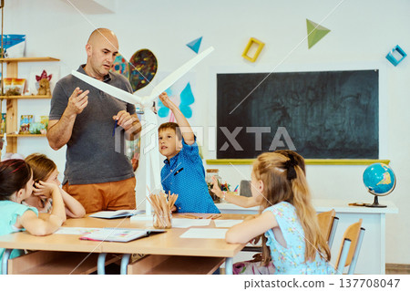Teacher and students explore a wind turbine model during hands-on science lesson in a classroom 137708047