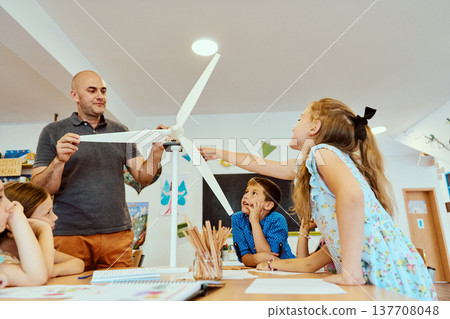 Teacher and elementary students exploring a wind turbine model during a hands-on STEM classroom lesson 137708048