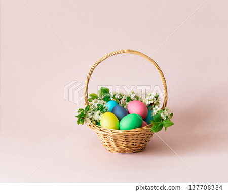 Easter painted eggs in a basket with flowers on pink background. Easter cute greeting card. Space for text. Easter painted eggs in a basket with flowers on pink background. Easter cute greeting card. Space for text. 137708384