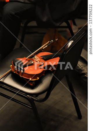 Violin resting on chair in concert hall backstage setting Violin resting on chair in concert hall backstage setting 137709222